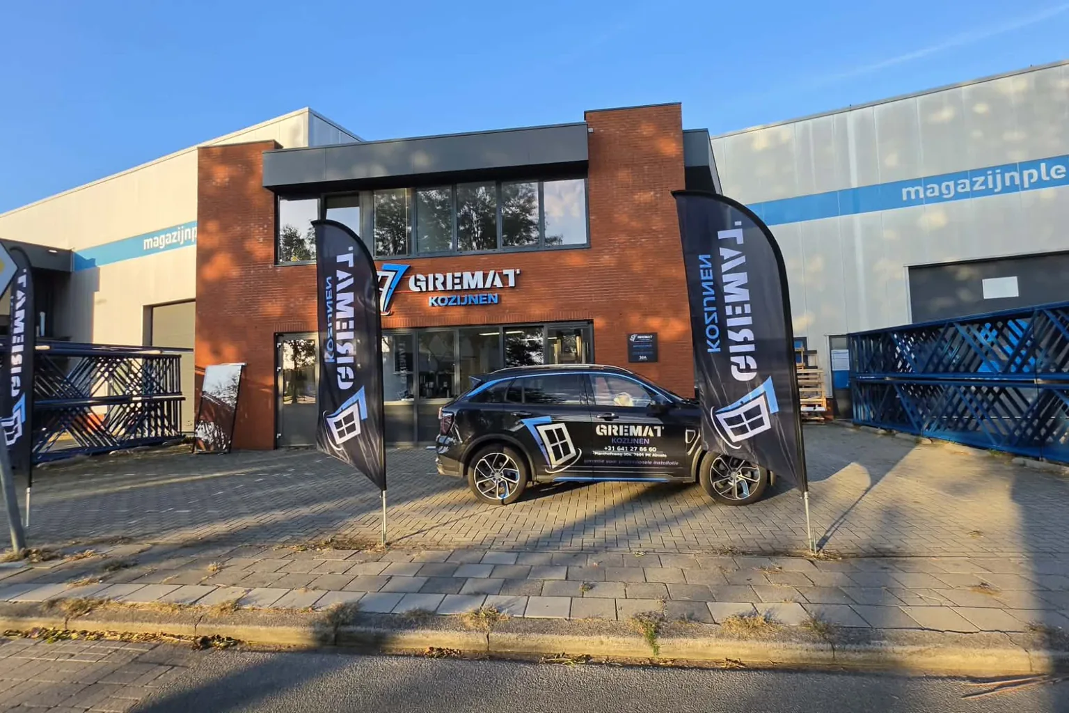 De showroom van Gremat Kozijnen aan de Planthofsweg in Almelo, met vlaggen en bedrijfsauto